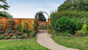 A garden pathway leading to a wooden gate with a metal archway. - Cann Office Hotel (Welshpool)