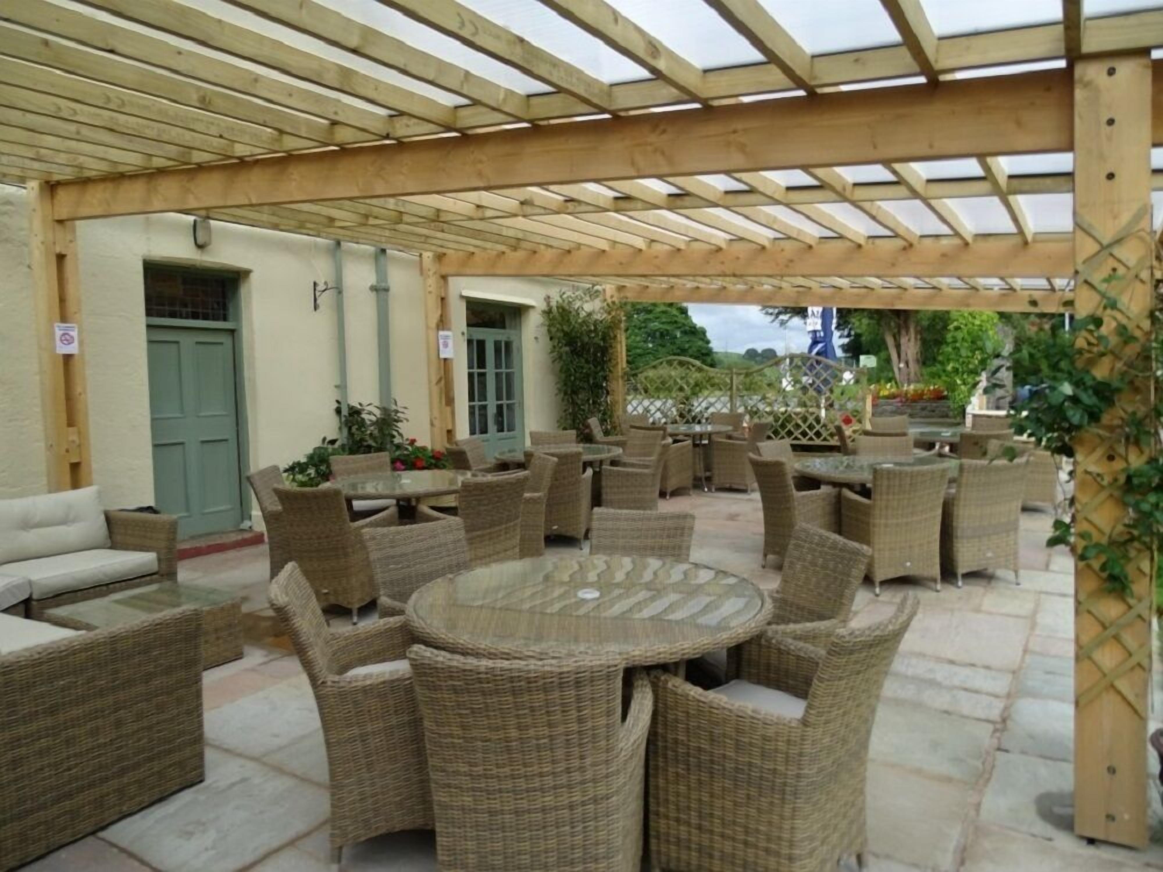 Un espace extérieur aménagé en terrasse, avec des meubles en osier et une pergola en bois.