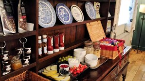 A wooden buffet table with various food items, including fruits, cheeses, and breads, and a selection of blue and white patterned plates on the shelves above. - Cann Office Hotel (Welshpool)