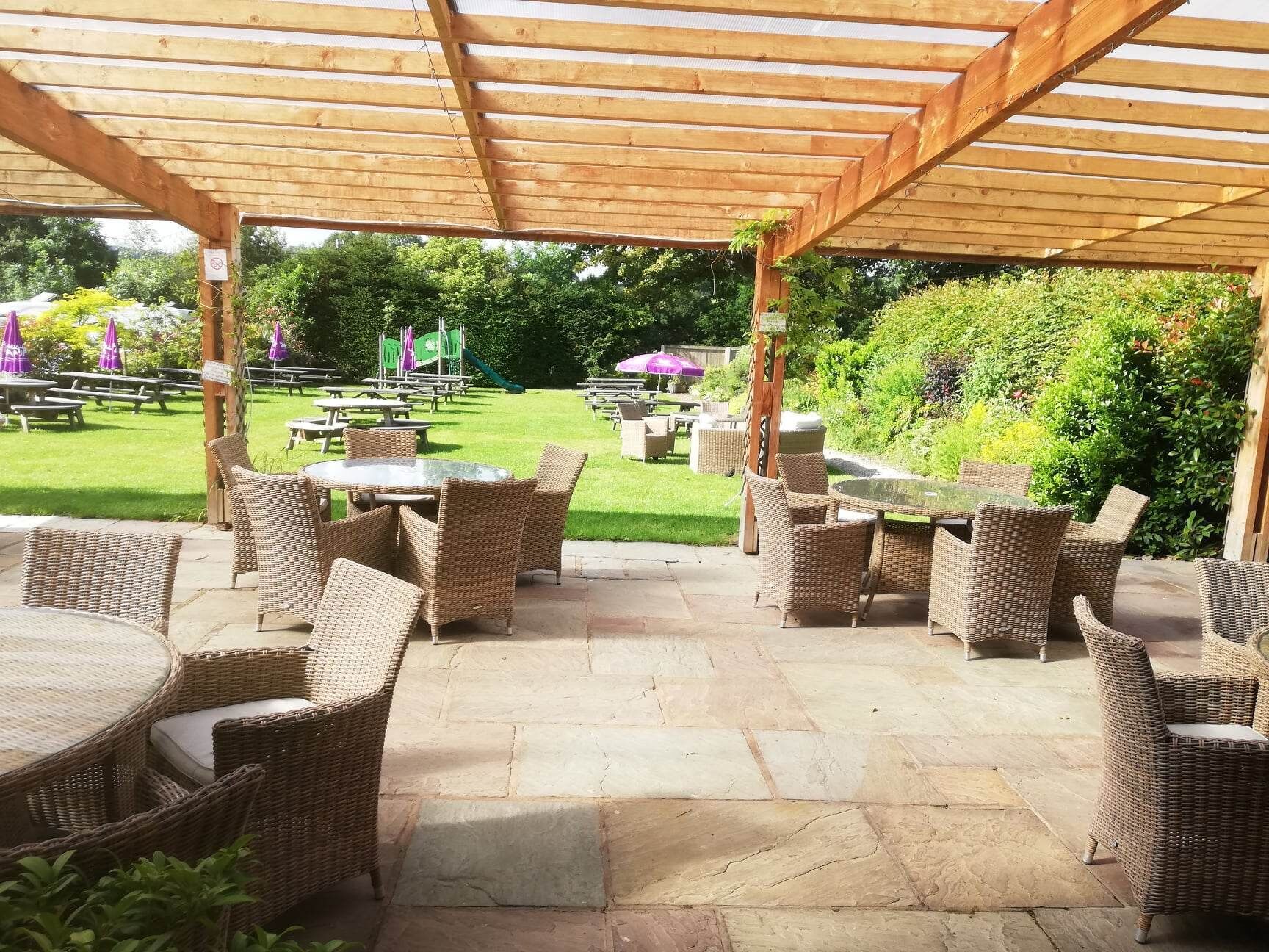 An outdoor patio area with wicker furniture and stone flooring.