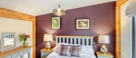 A bedroom with a bed, two bedside tables, a desk, and a chair.