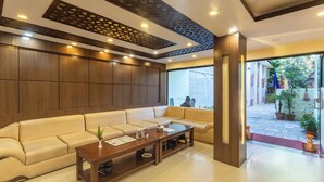 A modern lobby with a beige sofa, wooden coffee table, and decorative ceiling panels. - Hotel Sapana Garden (Kathmandu)