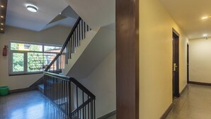 A hotel hallway with a staircase, a fire extinguisher, and a window with a view of buildings. - Hotel Sapana Garden (Kathmandu)