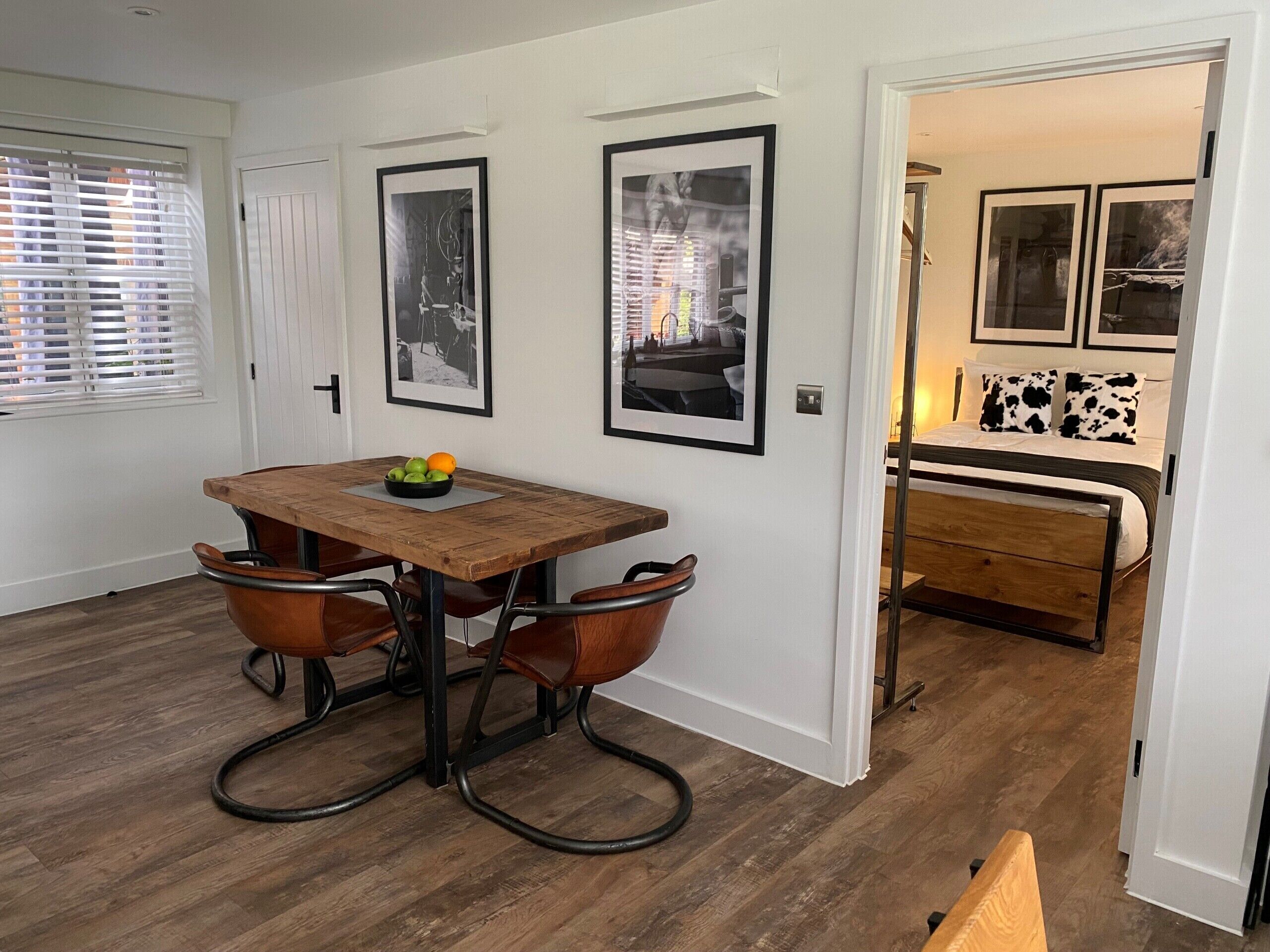 A dining area with a wooden table, two chairs, and a bowl of fruit.