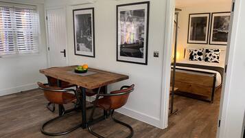 A dining area with a wooden table, two chairs, and a bowl of fruit.