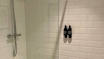 A glass-enclosed shower area with a handheld showerhead and a fixed showerhead.