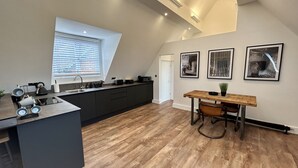 Une cuisine moderne dotée d’un îlot central, d’une table à manger et d’une fenêtre avec des stores.