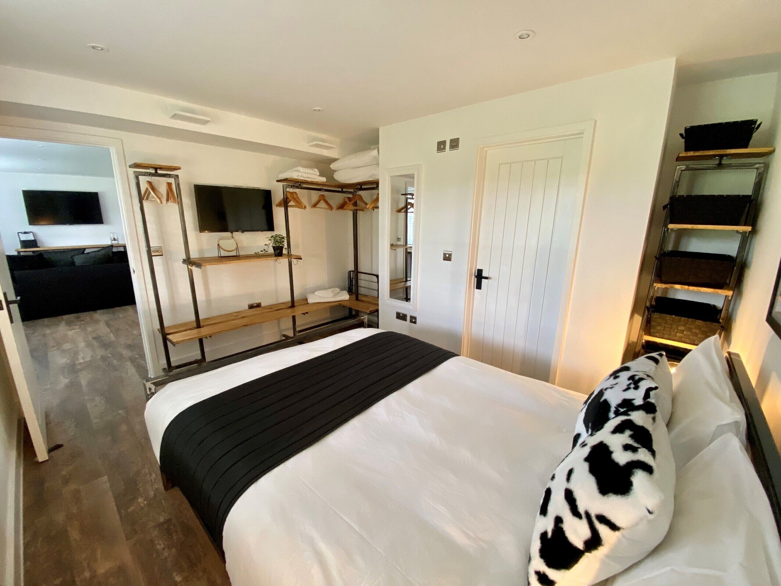 A hotel room with a bed, a TV, a wardrobe, and a small seating area.