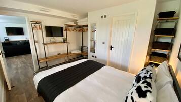 A hotel room with a bed, a TV, a wardrobe, and a small seating area.