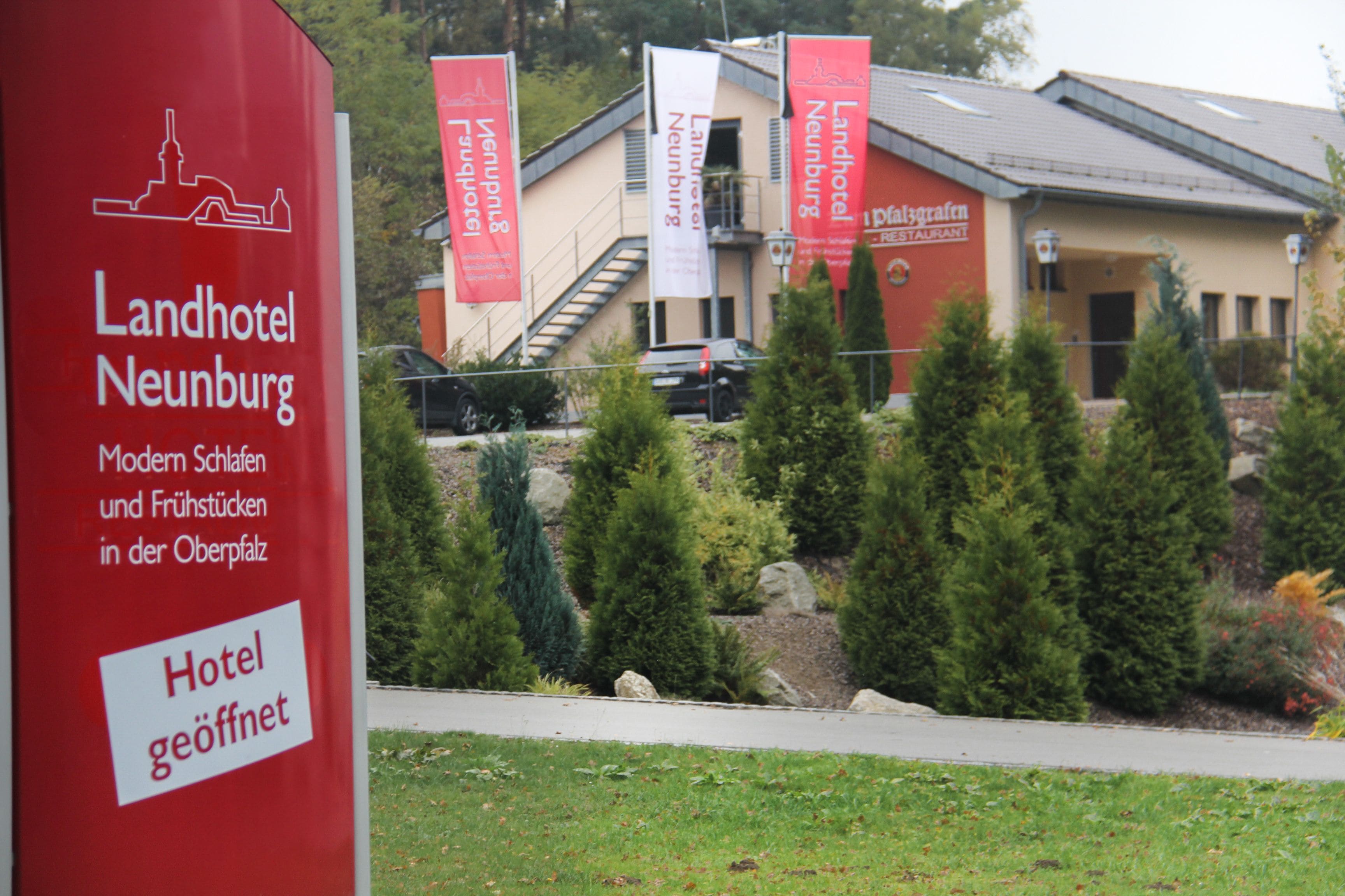 A hotel with a modern facade, a staircase leading to the entrance, and several red banners.