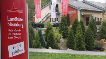 A hotel with a modern facade, a staircase leading to the entrance, and several red banners.