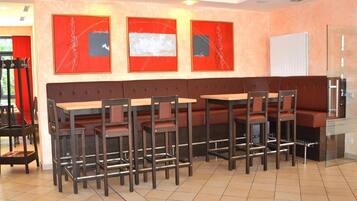 A restaurant with a long counter and multiple seating options.