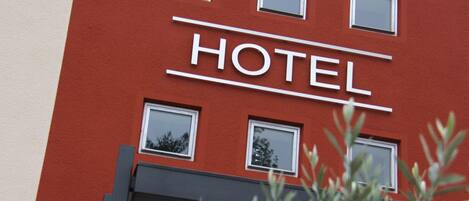 Un letrero de hotel con la palabra 'HOTEL' en letras grandes, flanqueado por ventanas.