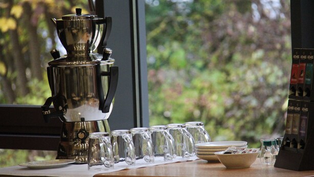A coffee station with a coffee maker, glasses, and a menu board. - Landhotel Neunburg (Neunburg vorm Wald)