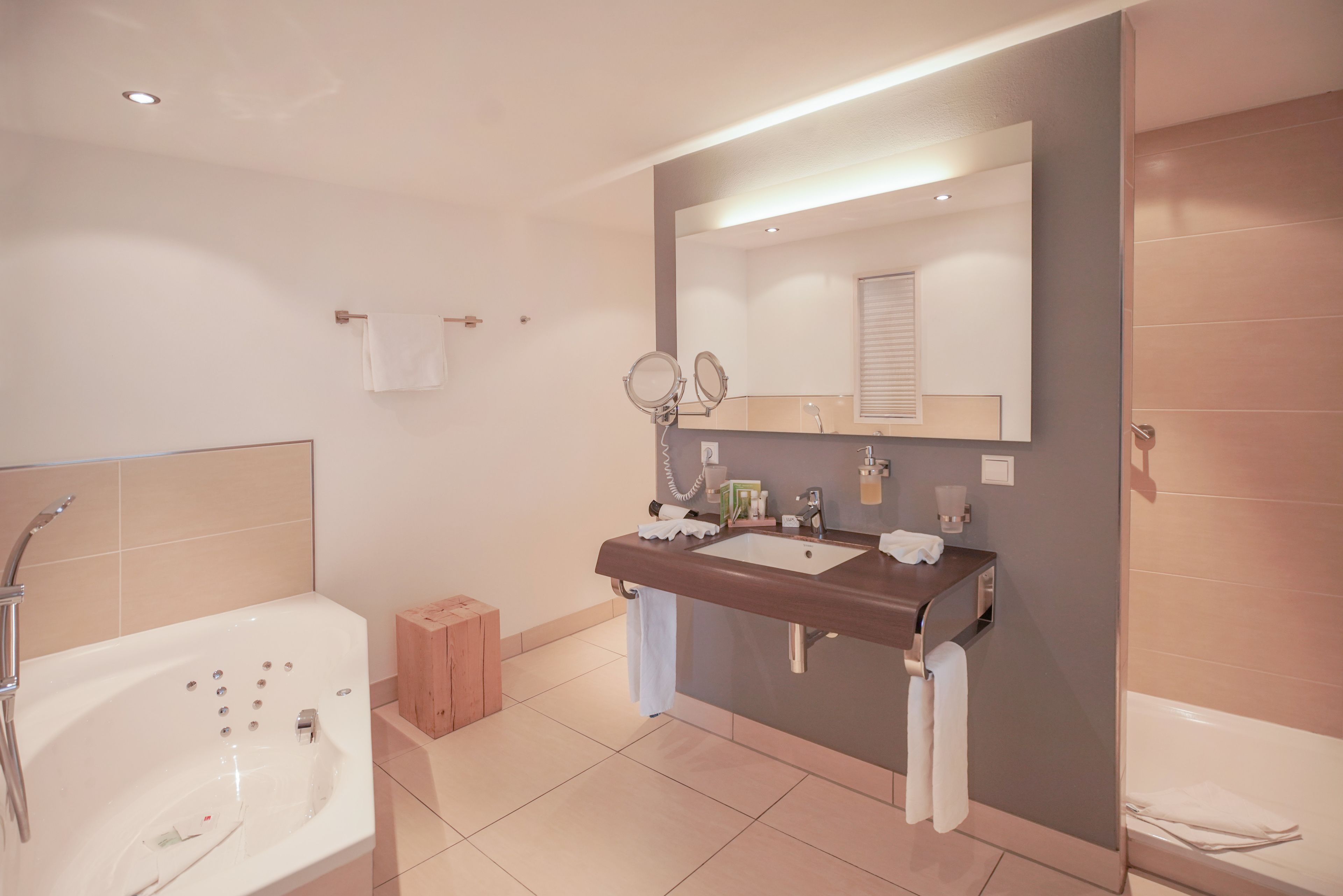 A modern bathroom with a bathtub, a vanity with a mirror, and a shower area.