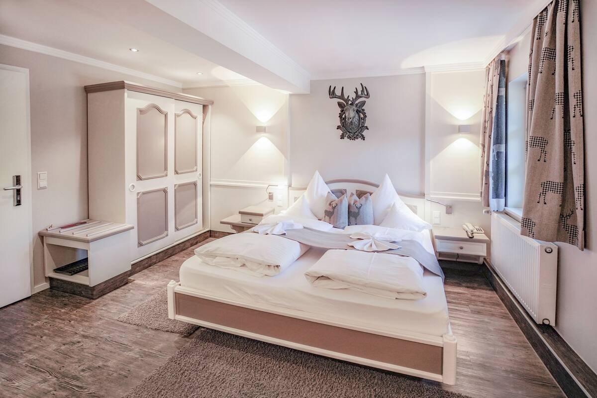 Un dormitorio con una cama grande, mesitas de noche, un armario y un espejo.