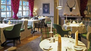 A dining area with multiple tables set for meals, featuring plaid upholstery and green chairs. - Hotel Engel (Sasbachwalden)