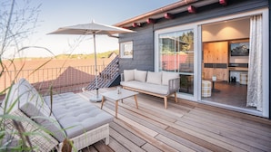 A modern outdoor deck with a sofa, coffee table, and umbrella. - Hotel Engel (Sasbachwalden)