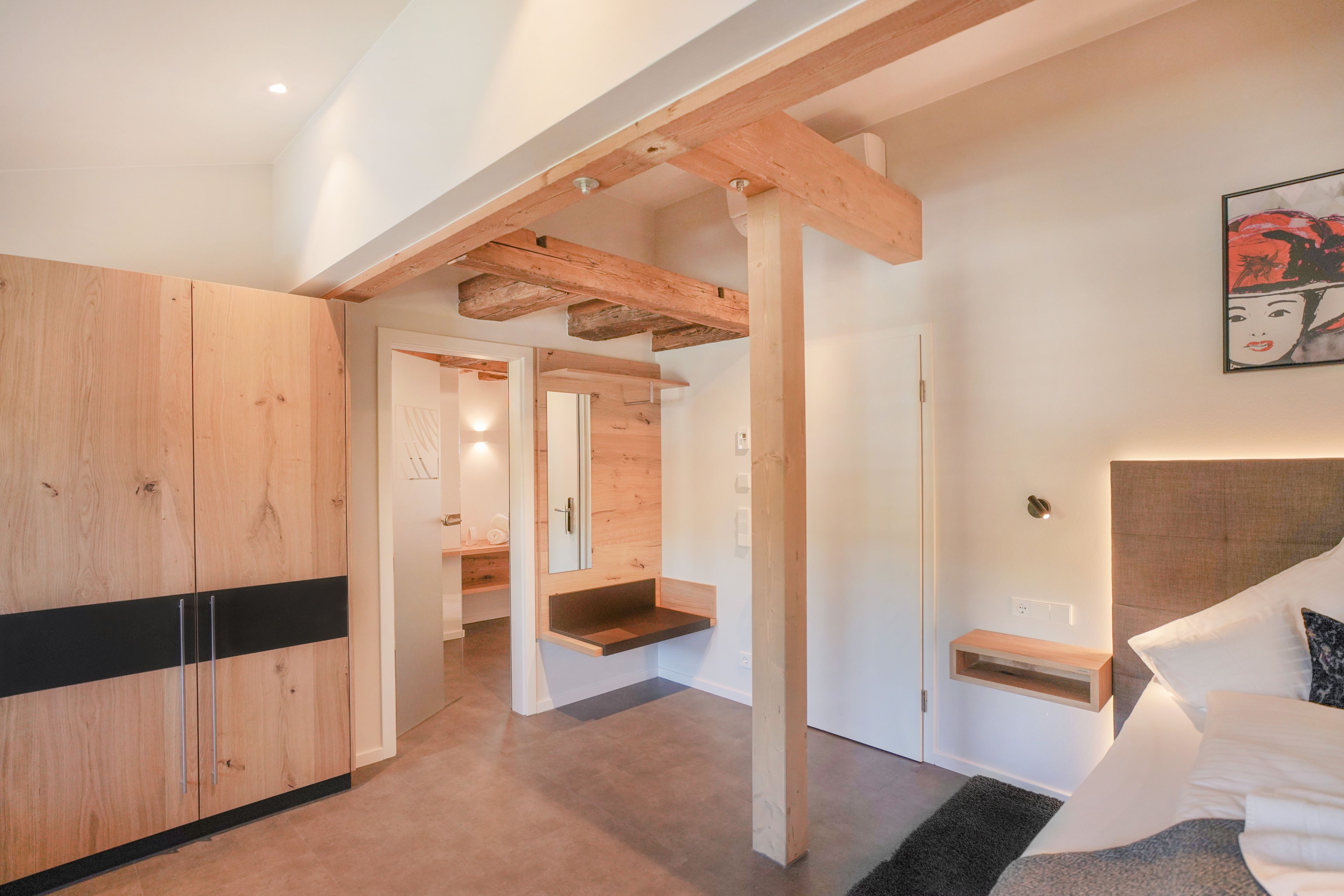 A modern bedroom with a large bed, a wooden wardrobe, and a built-in bench.