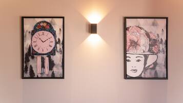 Two framed artworks on a wall, one depicting a clock and the other a floral design.
