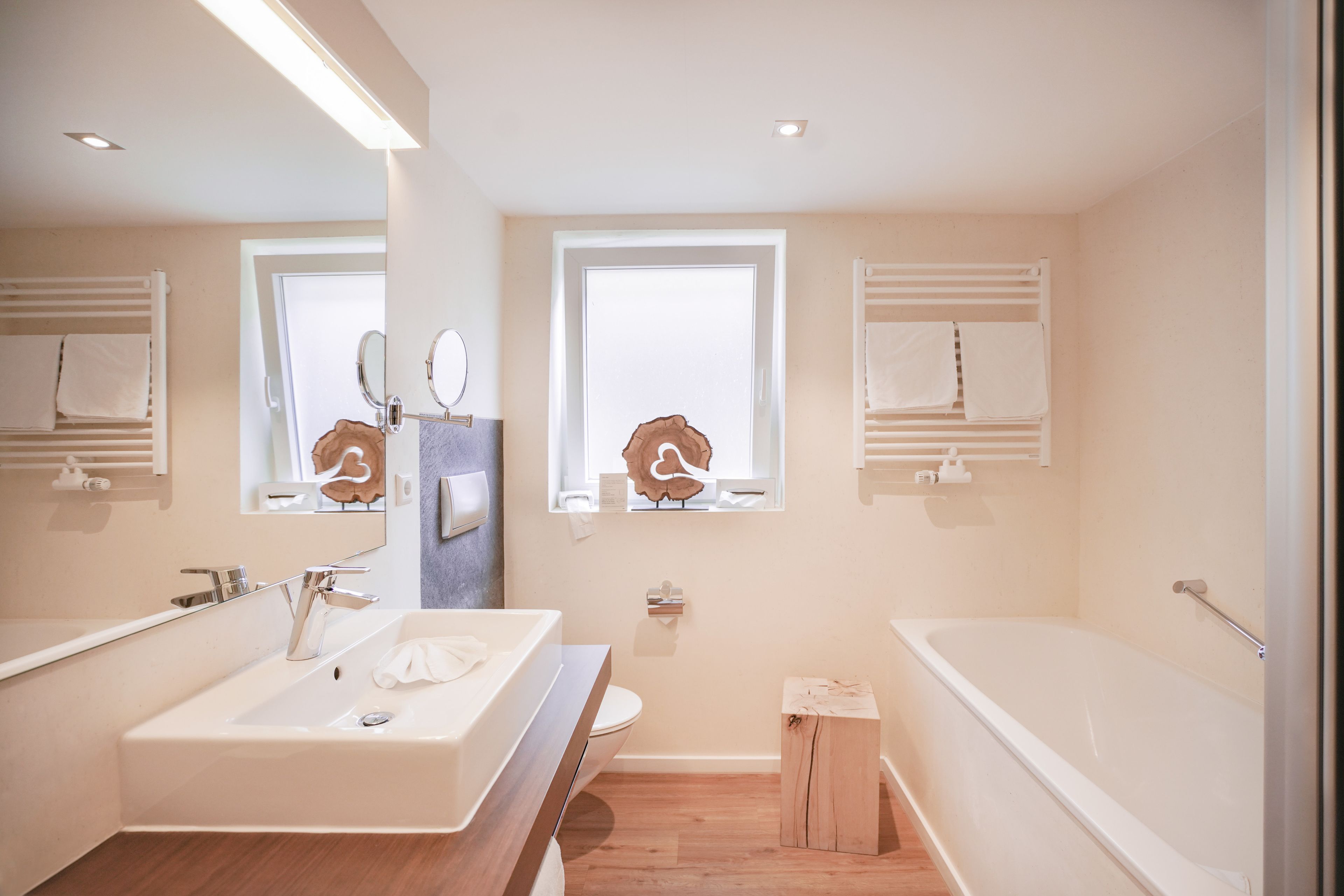 Une salle de bain moderne avec un grand lavabo, une baignoire et deux fenêtres.