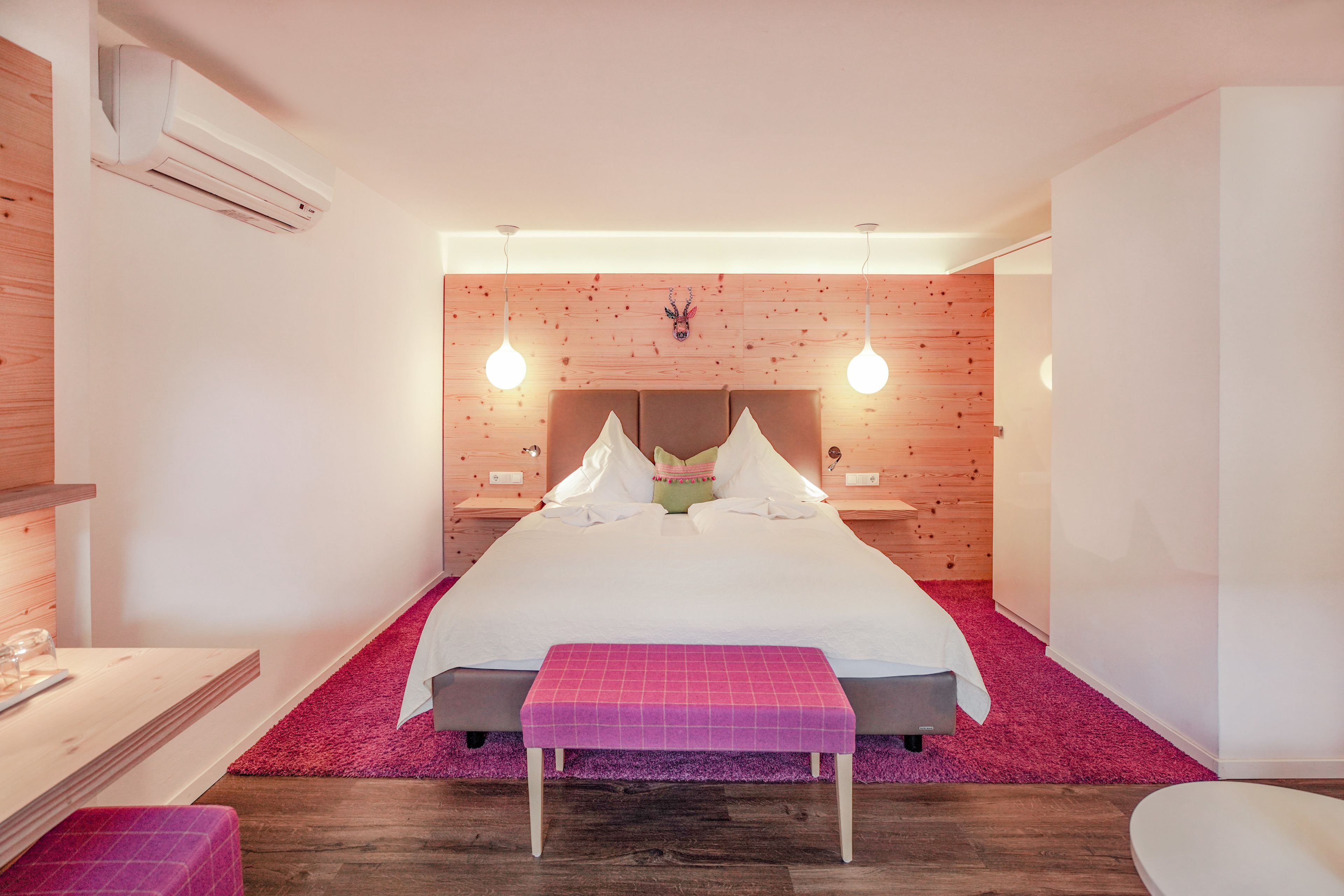Un dormitorio moderno con una cama grande, paneles de madera y lámparas colgantes.