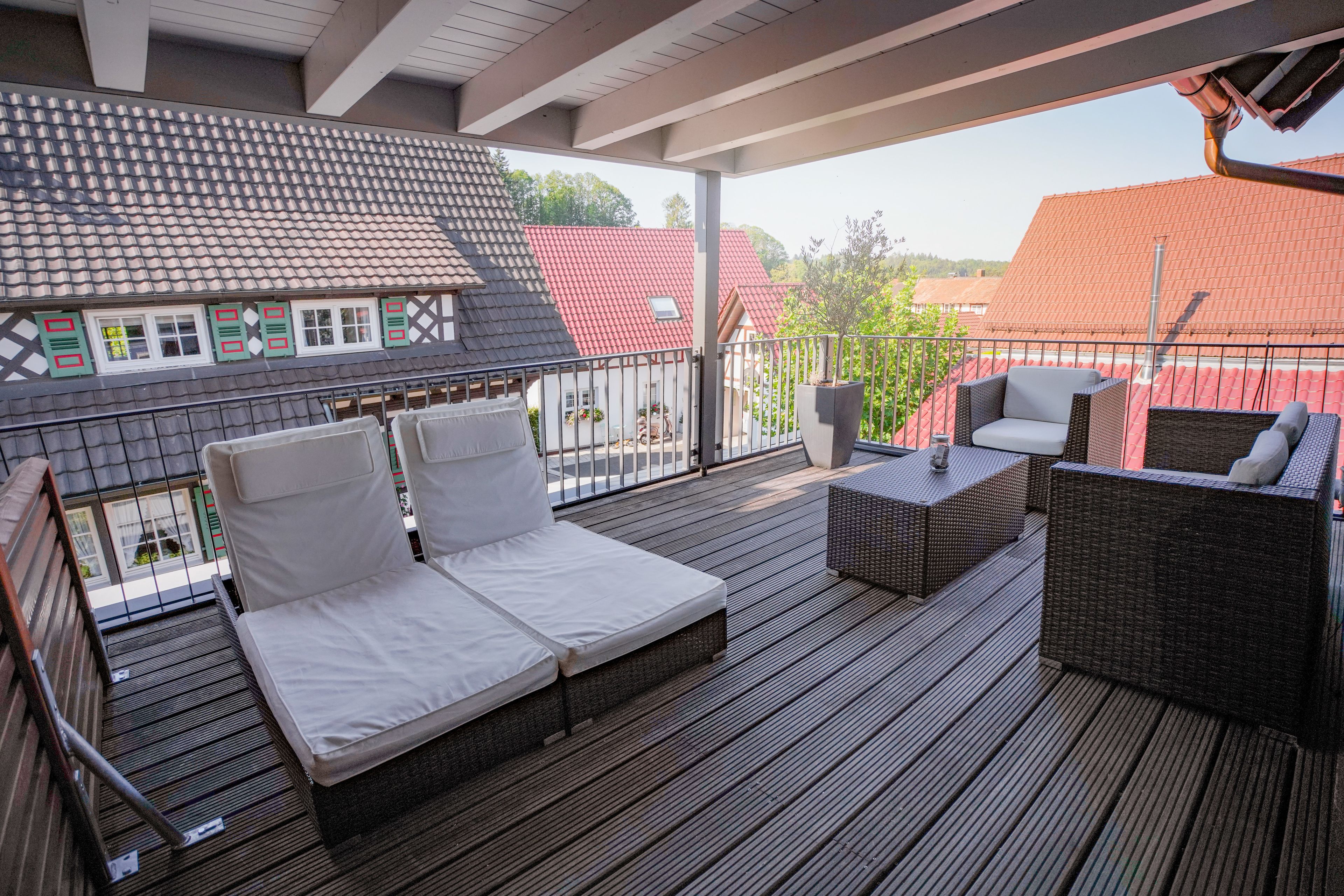 A covered outdoor deck with a sofa, a chair, and a small table.
