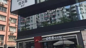 En byggnad med en skylt för UNIQLO LifeWear och en Pizza Hut-restaurang.