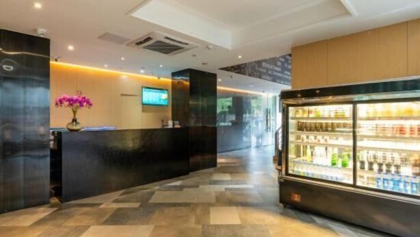 En hotellobby med modern design, inklusive en receptionsdisk, en digital skärm och ett kylskåp med hyllor för att visa upp produkter.