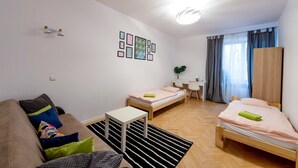 A compact studio apartment with a bed, a sofa, a small table, and a desk.