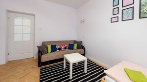 A living room with a sofa, a small white table, a black and white striped rug, and a door.