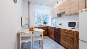 A modern kitchen with wooden cabinets, a white countertop, and a dining area with two chairs.