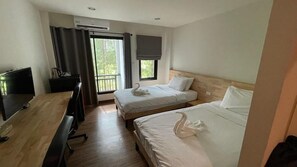 Une chambre d’hôtel avec deux lits, un bureau, une télévision et une fenêtre avec des rideaux.