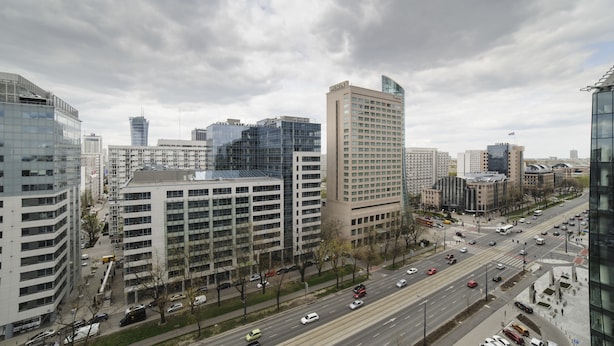 A cityscape with modern high-rise buildings, a busy street, and a clear sky. - Art&Apart (Warsaw)