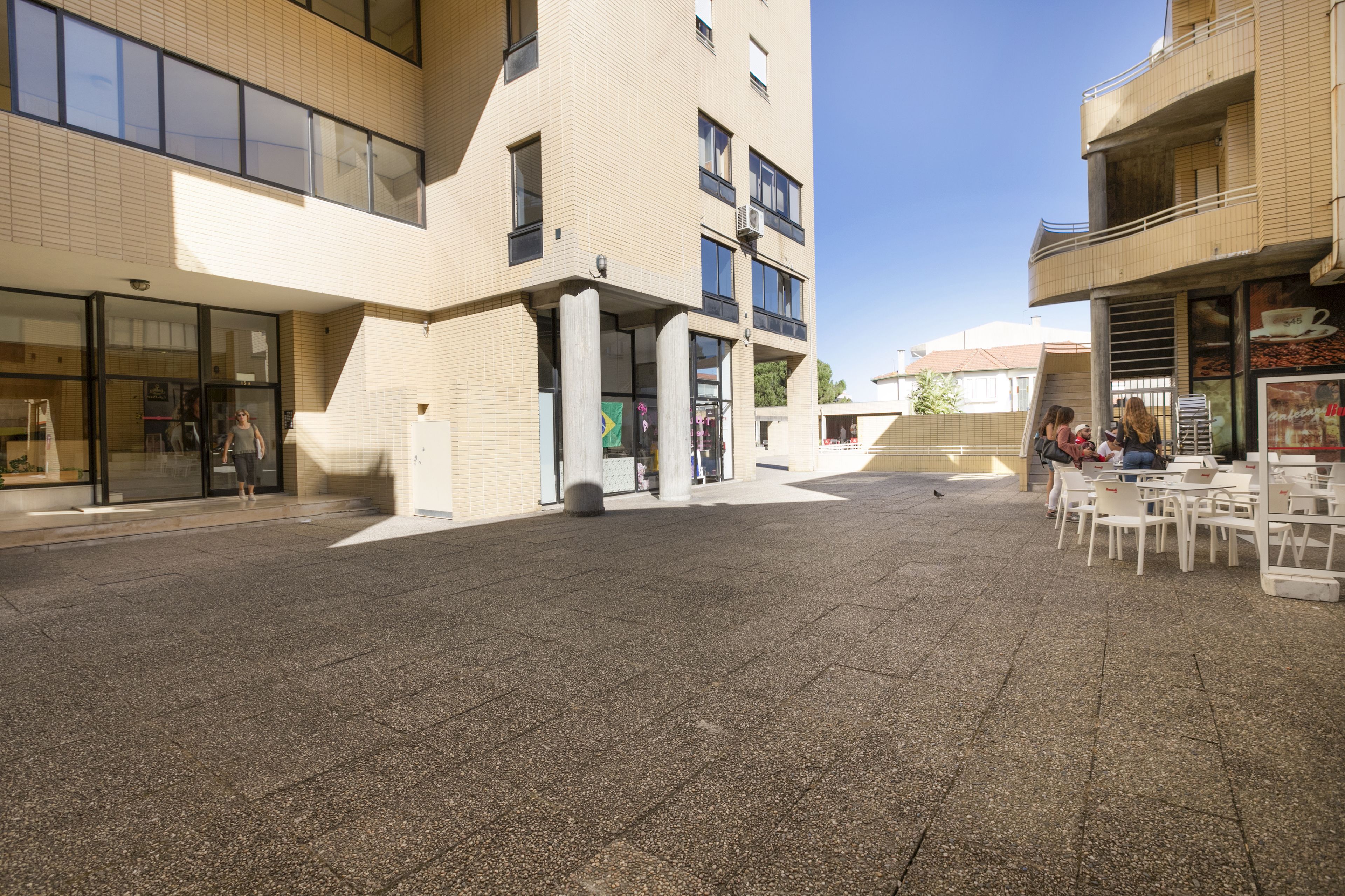 A courtyard with a building featuring large windows and a tiled floor.