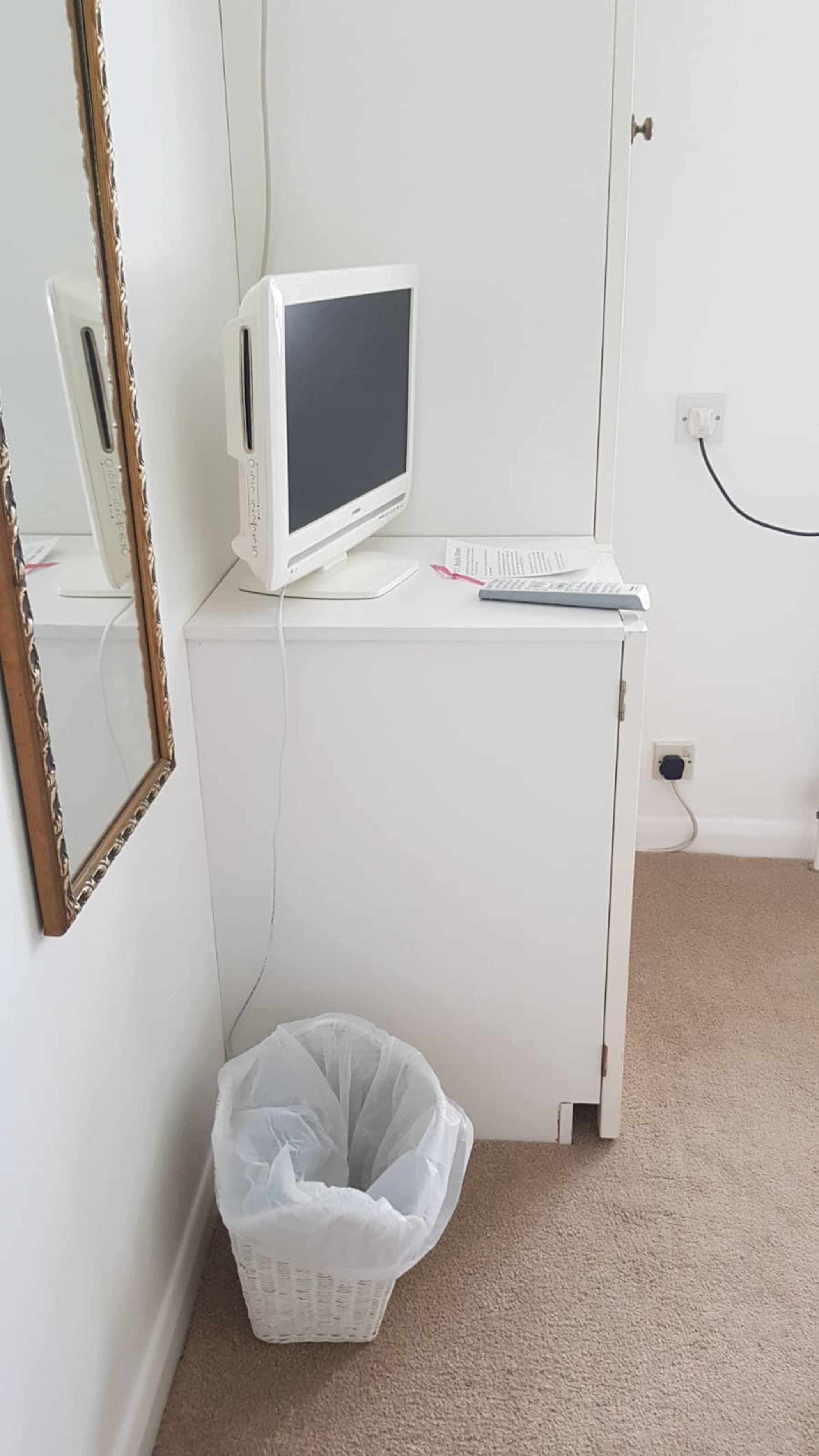 A white desk with a computer monitor, keyboard, and a trash bin.