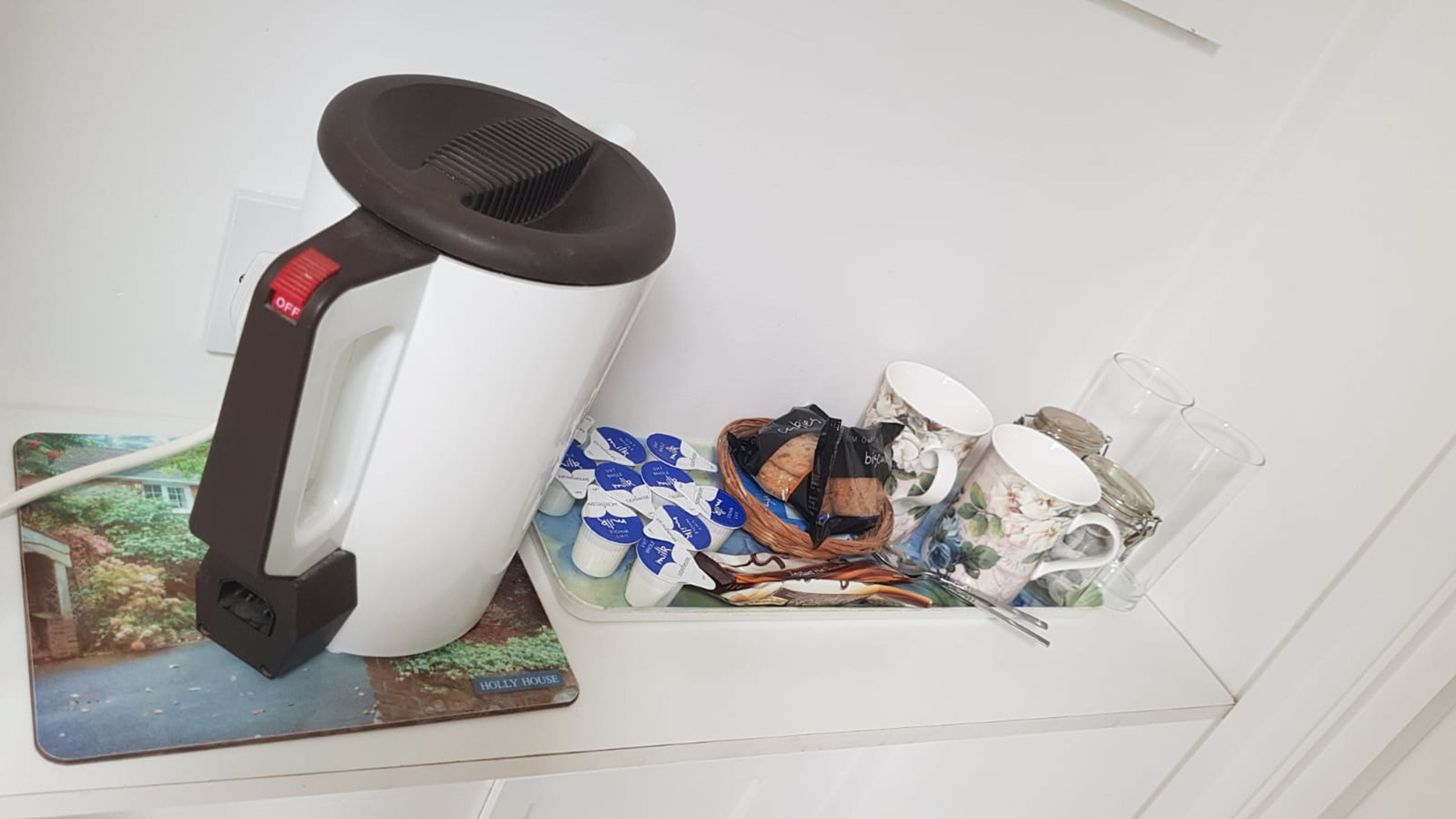 A hair dryer on a white surface, a tray with food items, and a mug.