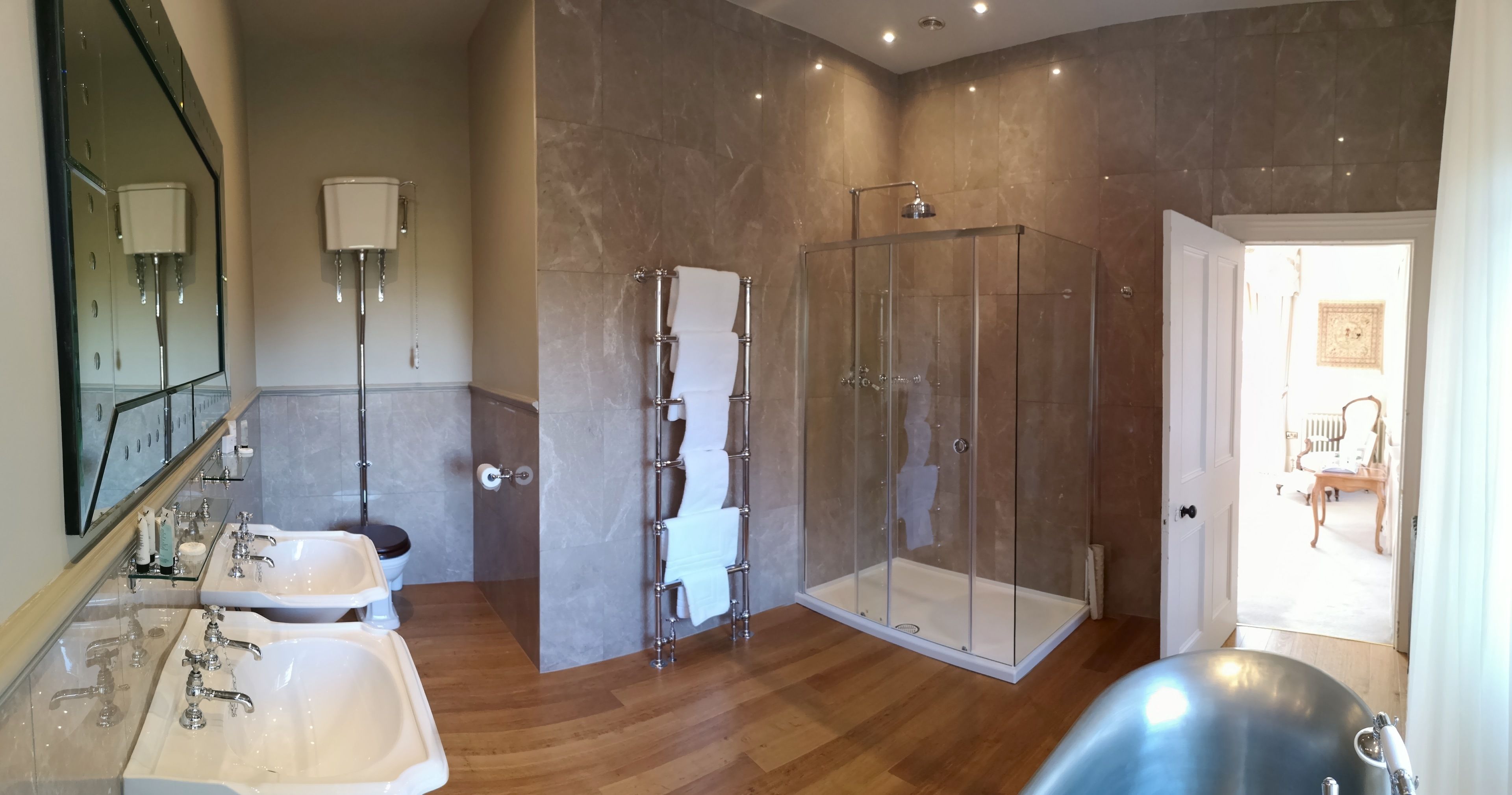 A spacious bathroom with two sinks, a glass-enclosed shower, and a large bathtub.