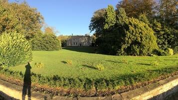 A pathway leading to a large estate with a well-maintained lawn and trees.