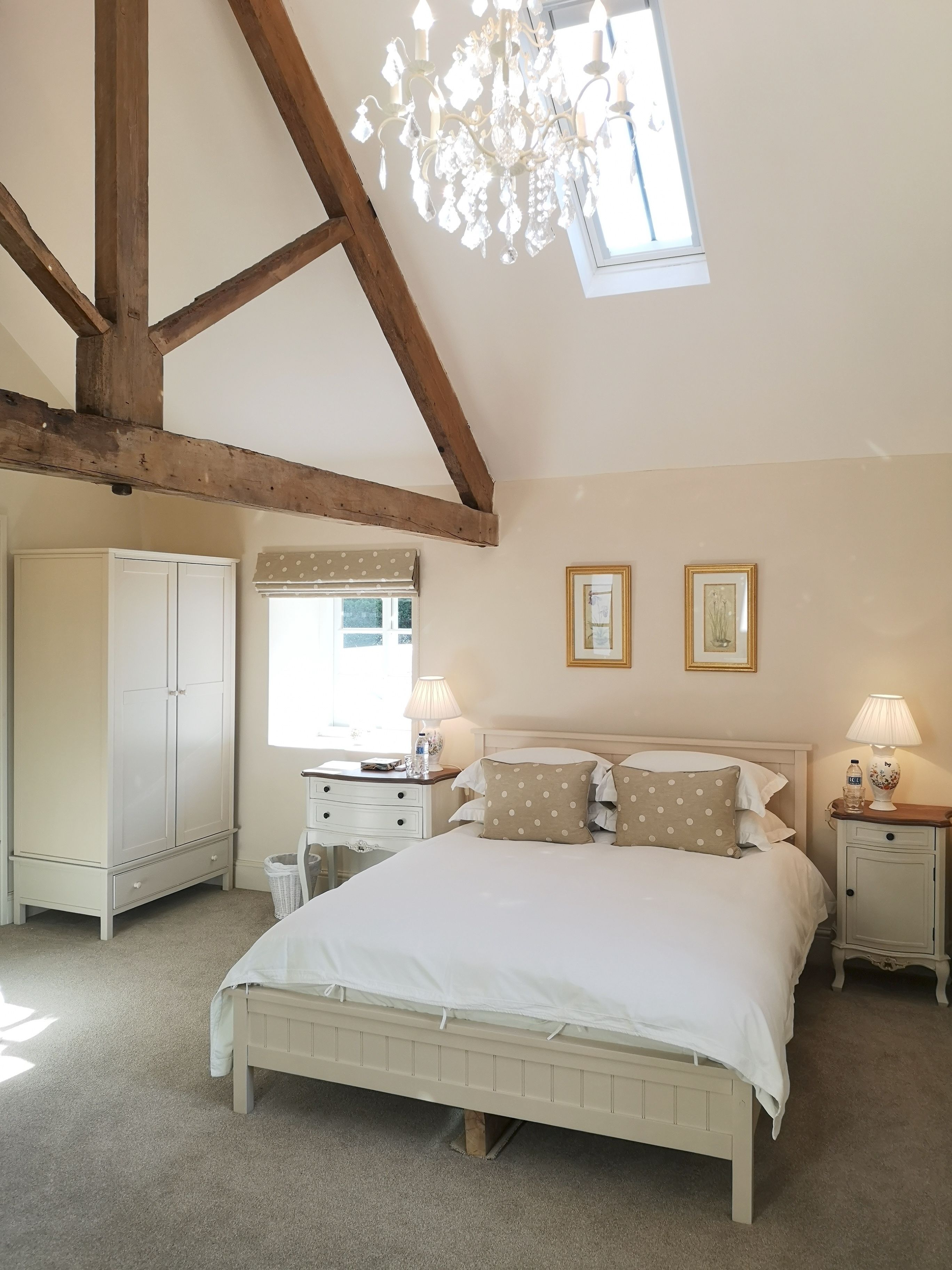 Une chambre à coucher comprenant un lit, des tables de chevet, une armoire, un lustre et une fenêtre.