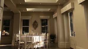 A spacious room with a high ceiling and a skylight. There is a dining table with chairs and a large mirror on the wall. - Cleatham Hall (Gainsborough)