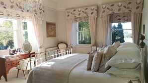 A bedroom with a large bed, a dresser, a mirror, and a chandelier. - Cleatham Hall (Gainsborough)
