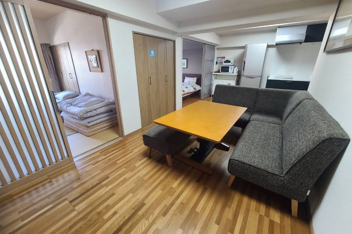 Ein gemütlicher, kleiner Wohnraum mit Holzboden, einer Couch, einem kleinen Tisch und einem Bett im Hintergrund.