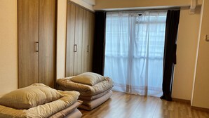 Une chambre avec une armoire en bois, un lit avec une literie à rayures et une fenêtre ornée de rideaux légers.