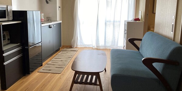 Een knus leefruimte met een kitchenette, een bank en een tafeltje.