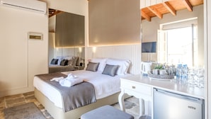 A bedroom with a bed, bedside table, mirror, and built-in air conditioning unit. - Limassol Old Town Mansion (Limassol)