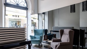 A modern interior with a large window, two armchairs, a small round table, and a patterned floor. - Limassol Old Town Mansion (Limassol)