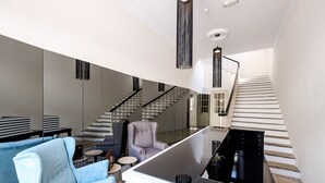 A modern interior with a staircase, a seating area with a light blue armchair, and a black kitchen island. - Limassol Old Town Mansion (Limassol)