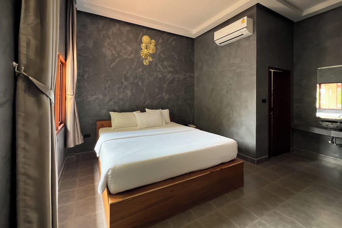 Quarto moderno com uma cama grande, paredes escuras e uma janela.