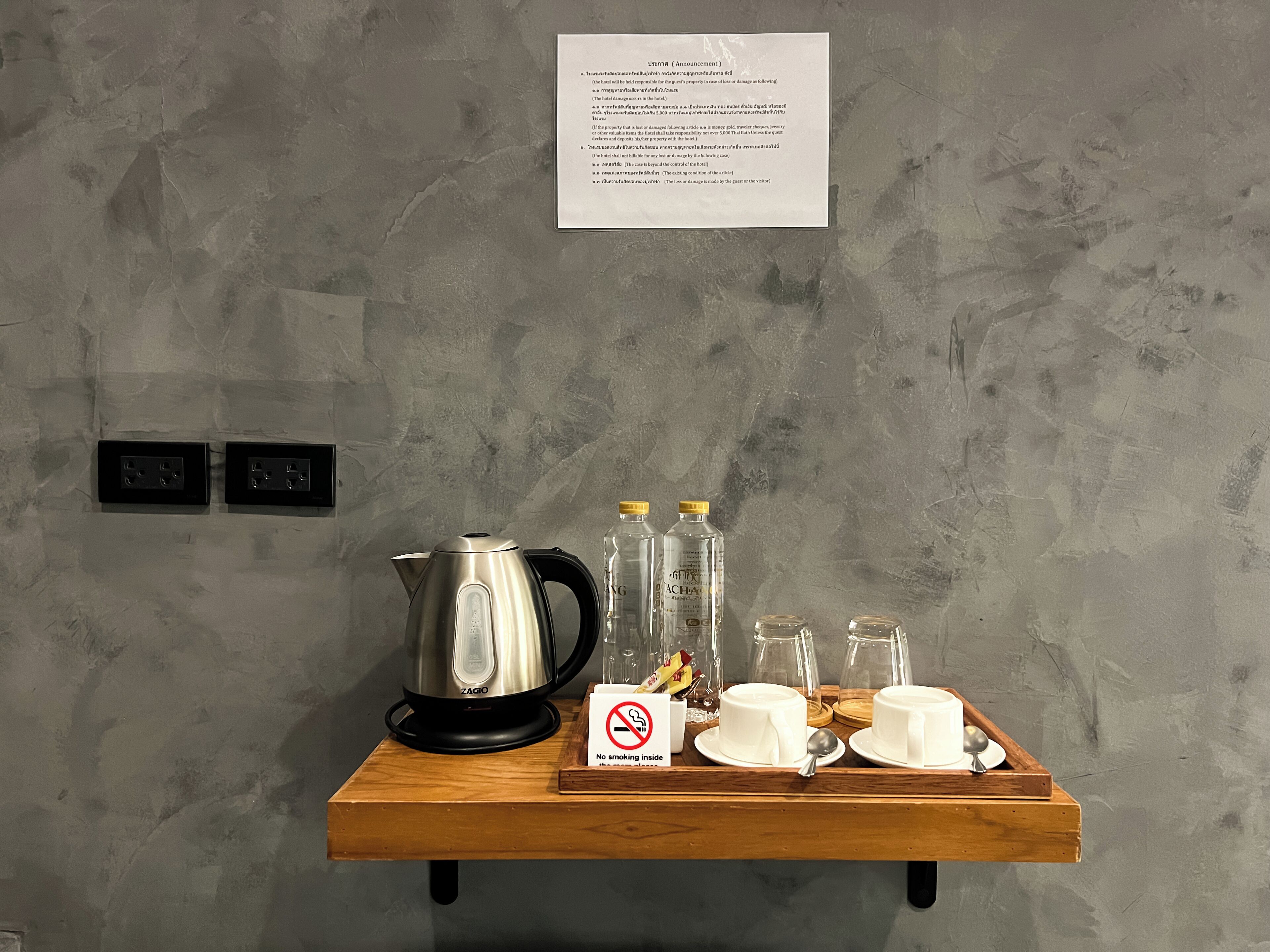 Una bandeja de madera con cafetera, botellas de leche y tazas blancas.